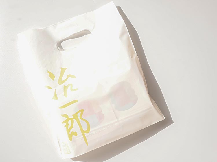 治一郎のショッパー(手提げ袋)。白地に黄色のロゴが入った上品なデザイン